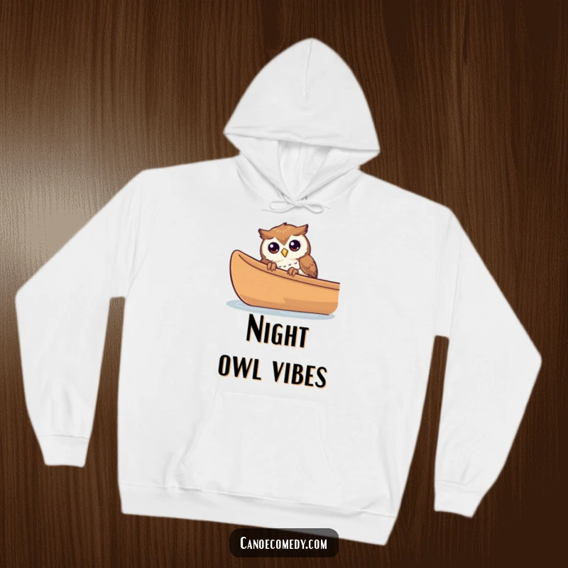 Funny curious owl peeking over the edge of a canoe on a hoodie, conveying quiet observation.