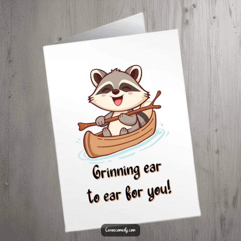 Funny Free Printable Birthday Card: Cheerful kawaii raccoon steering canoe with twig, big grin for birthday.