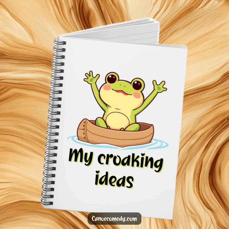 Kawaii frog excitedly waving its arms while paddling a canoe, featured on a notebook for jotting ideas.